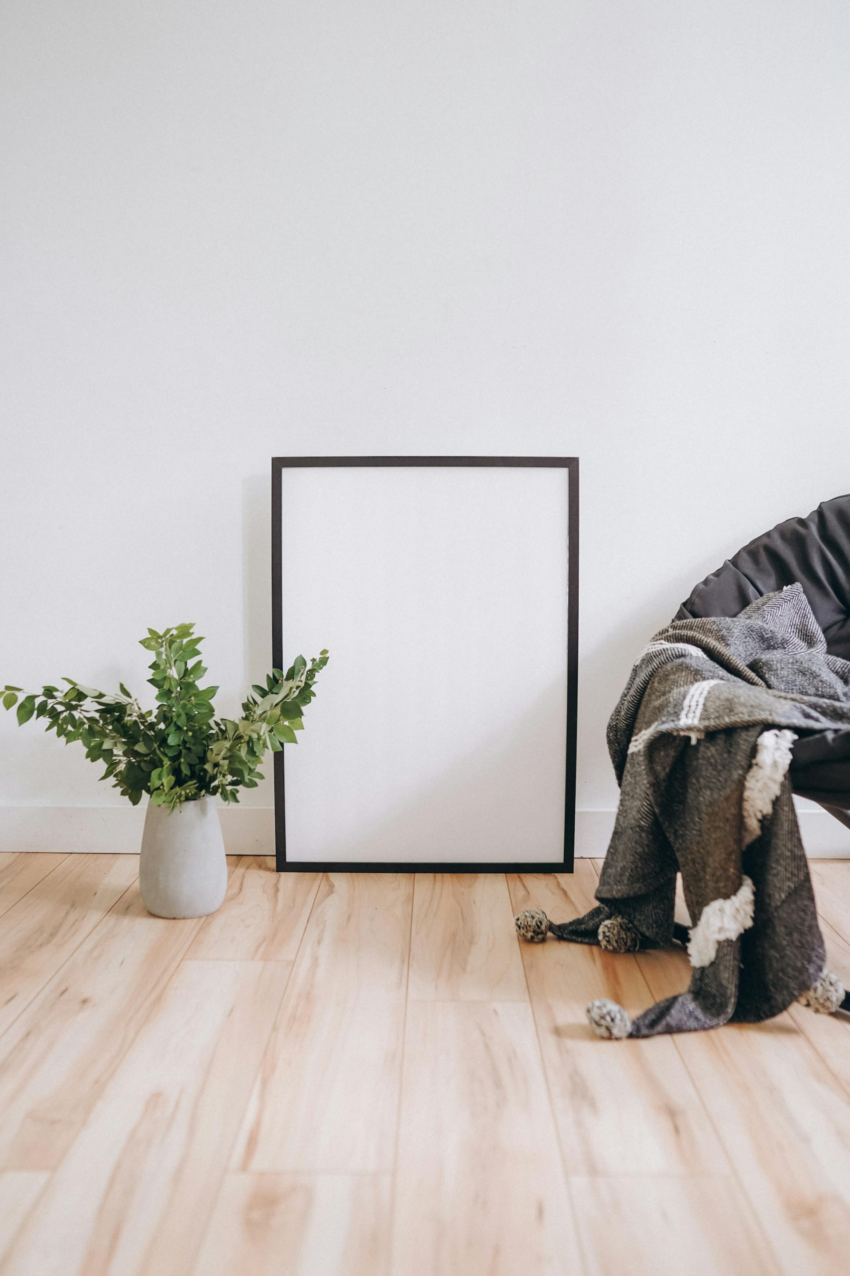 Blank frame mockup in a room with a chair and plant.